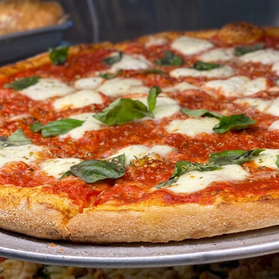 Neapolitan-style pizza topped with tomato sauce, melted mozzarella, and fresh basil on a metal serving tray.